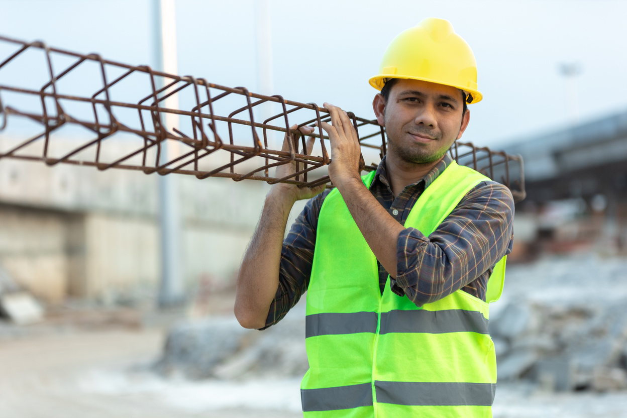 asian construction worker carrying steel in construction site